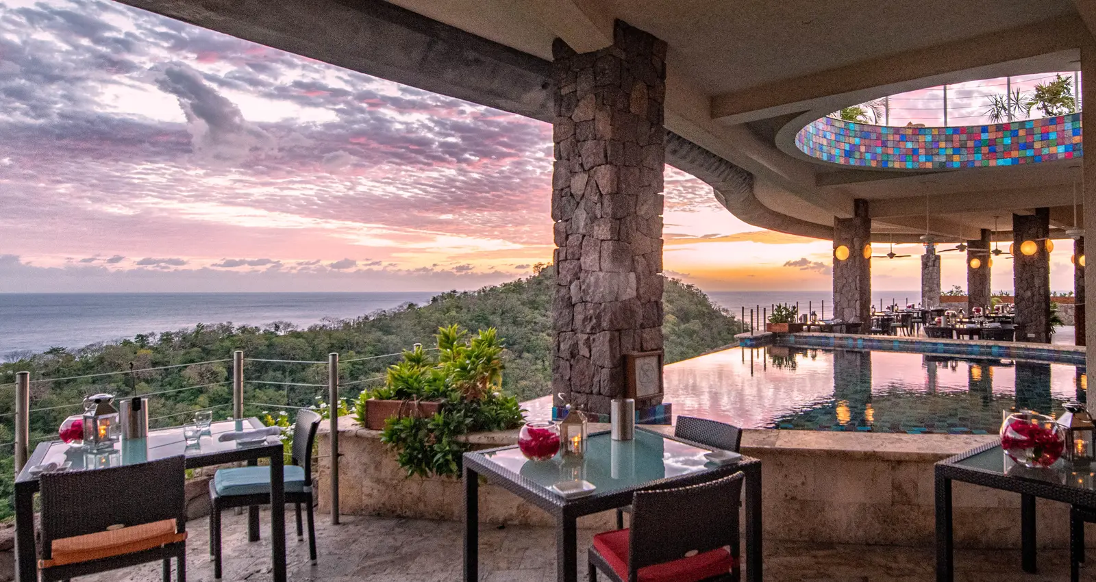 The Jade Mountain Club at dusk: tables laid under the concrete canopy, the infinity pool in the middle, a dome of coloured tiles and a pink sea.
