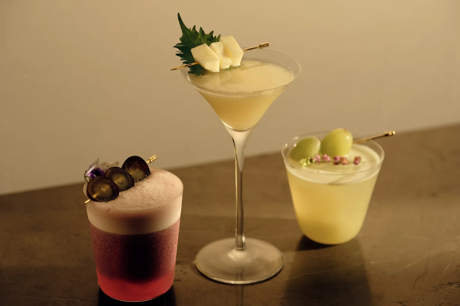3 autumn cocktails at Janu Bar: a grape sour, a shiso martini and a glass garnished with grapes.