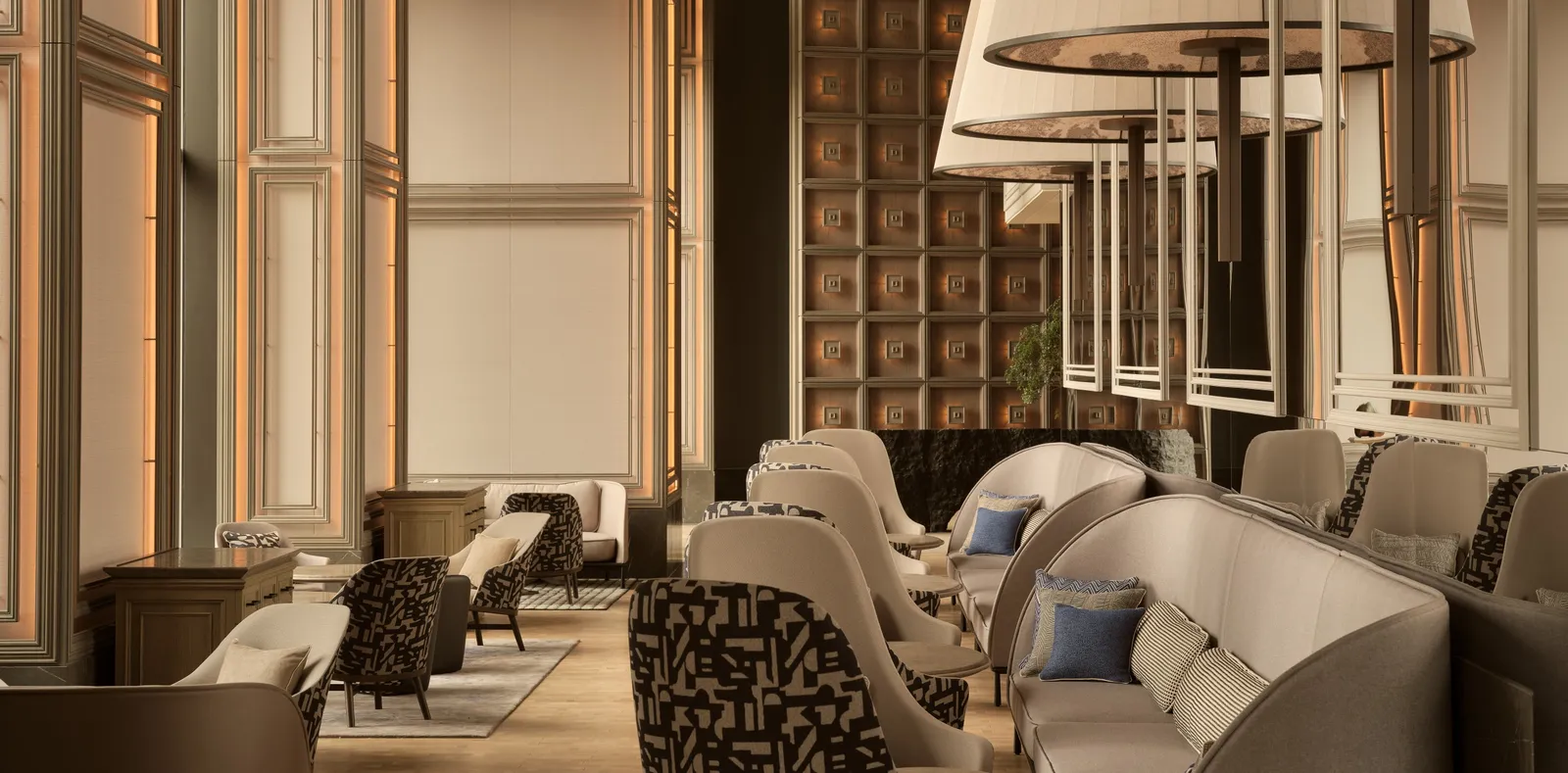 The Janu Lounge on the fifth floor: sofas and armchairs under the high ceiling, the panelled walls and the big hanging lamps.