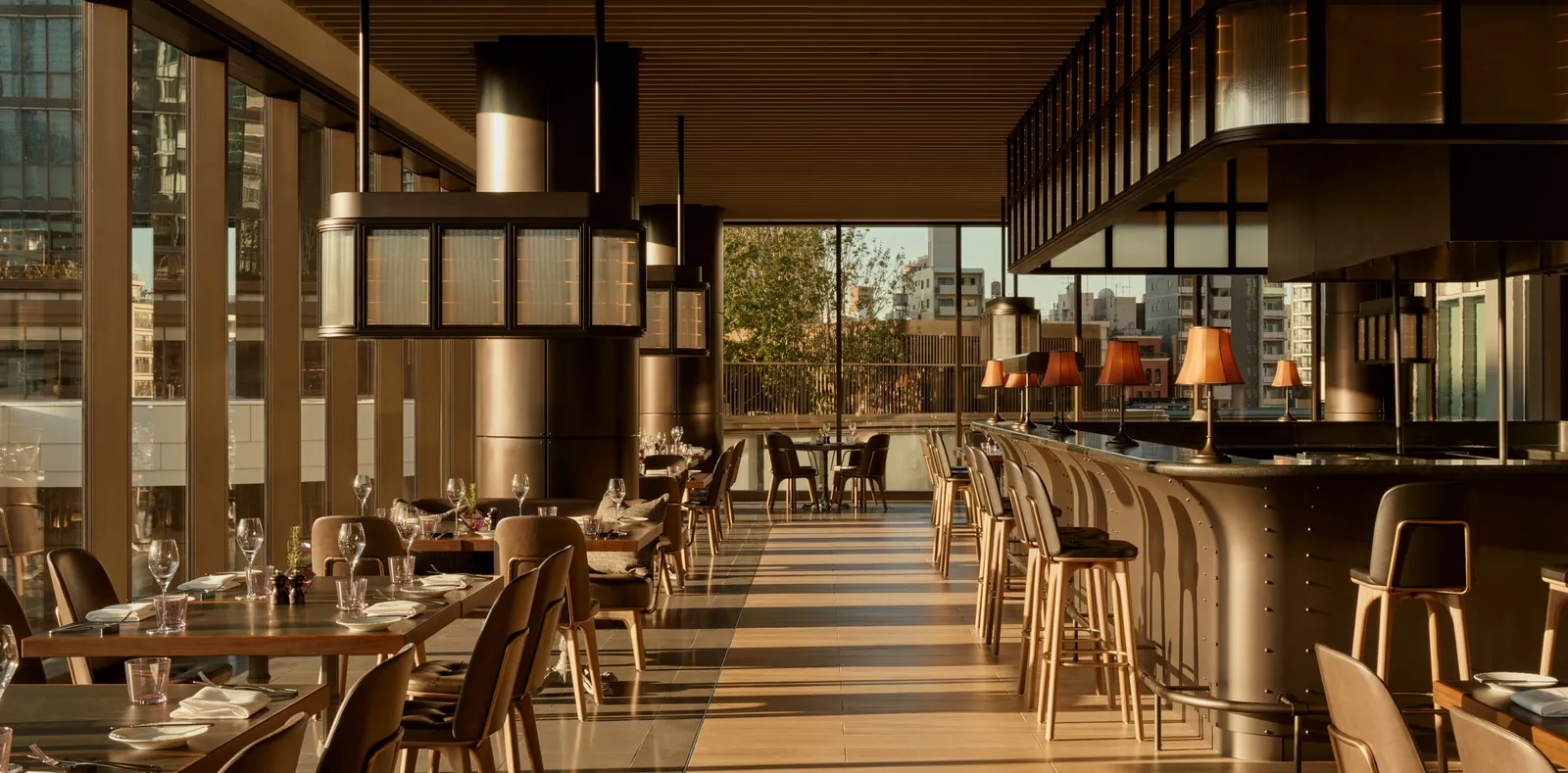 Janu Grill: the long room with its counter, the stools and the windows onto the green.