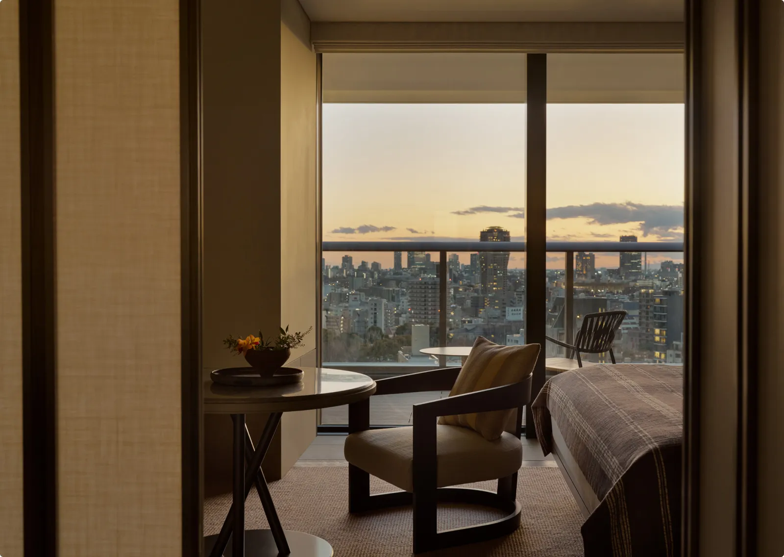 A City Room at sunset: the armchair beside the bed and the balcony open onto the city.