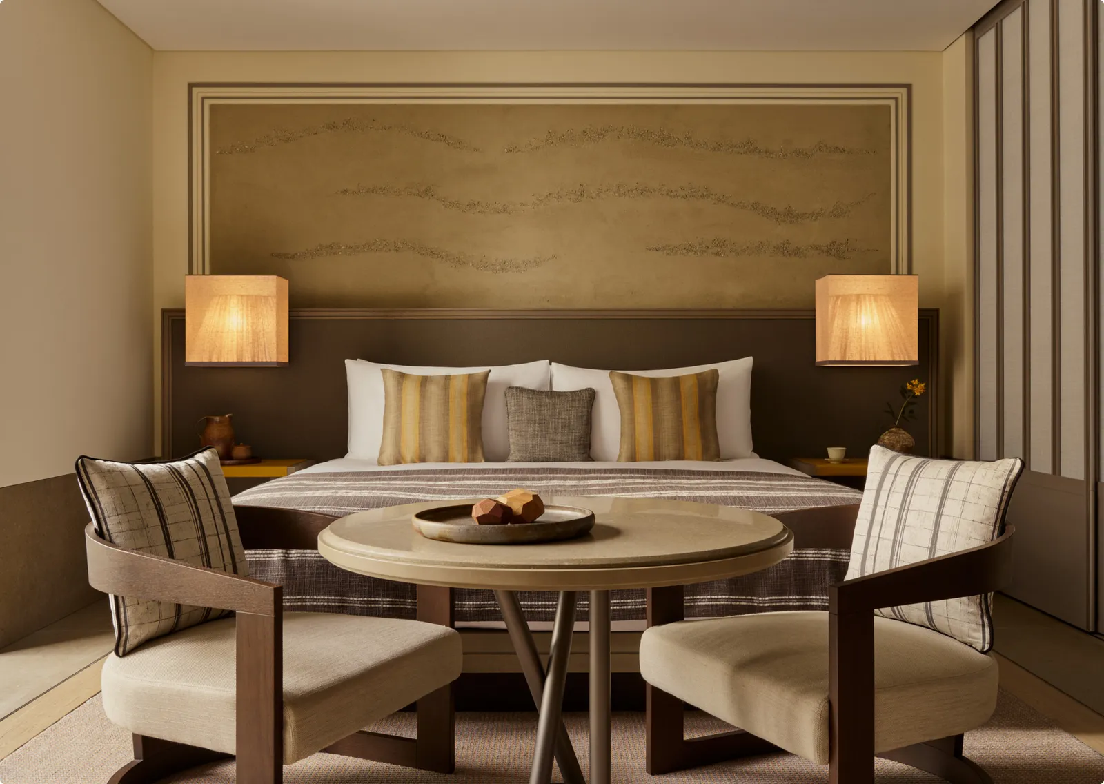 A Deluxe Room: the king bed, 2 armchairs and a round table with a plate of fruit.