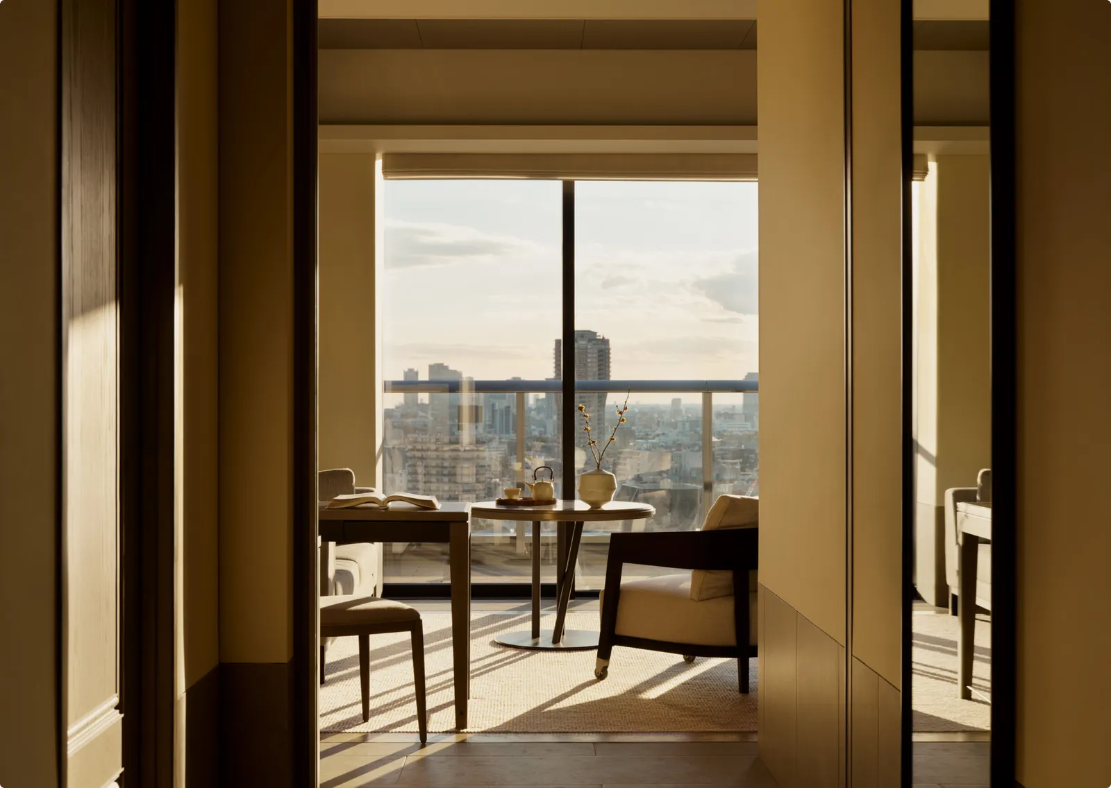 A Deluxe Suite seen from the hallway: the table, an armchair and the balcony over the city.