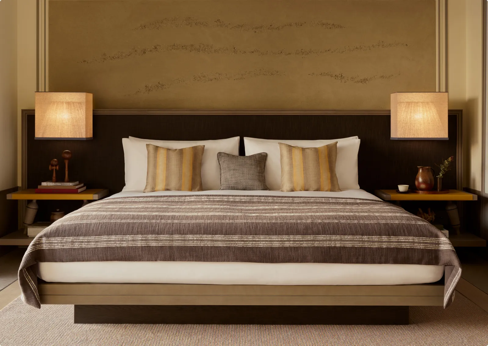 A Premier Suite bedroom: the king bed with its paper lamps and the plaster panel behind.