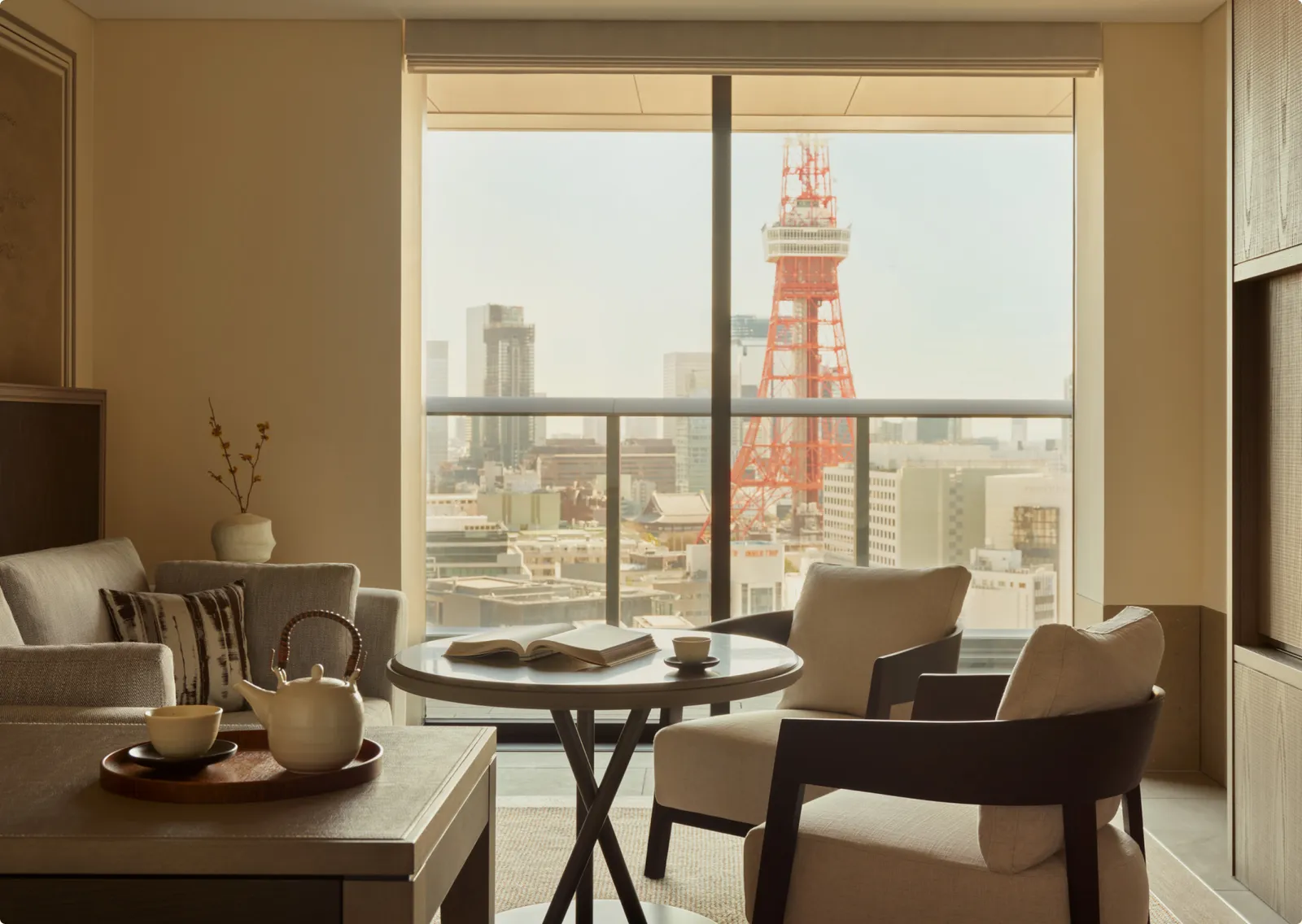 A Tower View Suite living room: a small table, 2 armchairs and Tokyo Tower beyond the balcony.