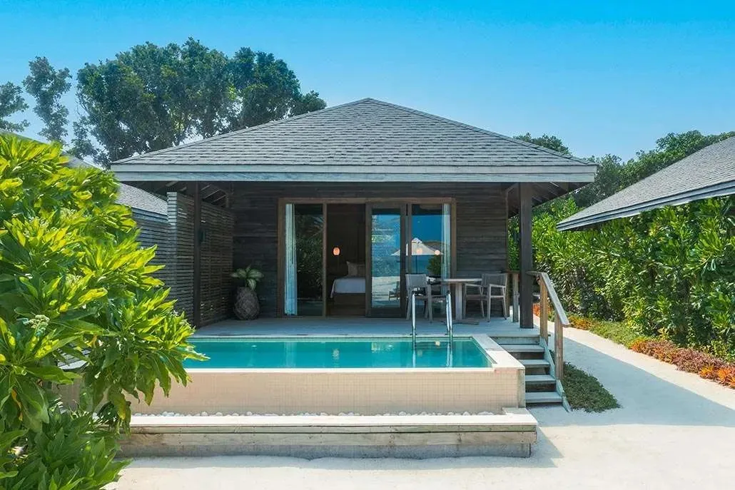 A Beach Pool Villa with its pool in front of the deck, among the plants
