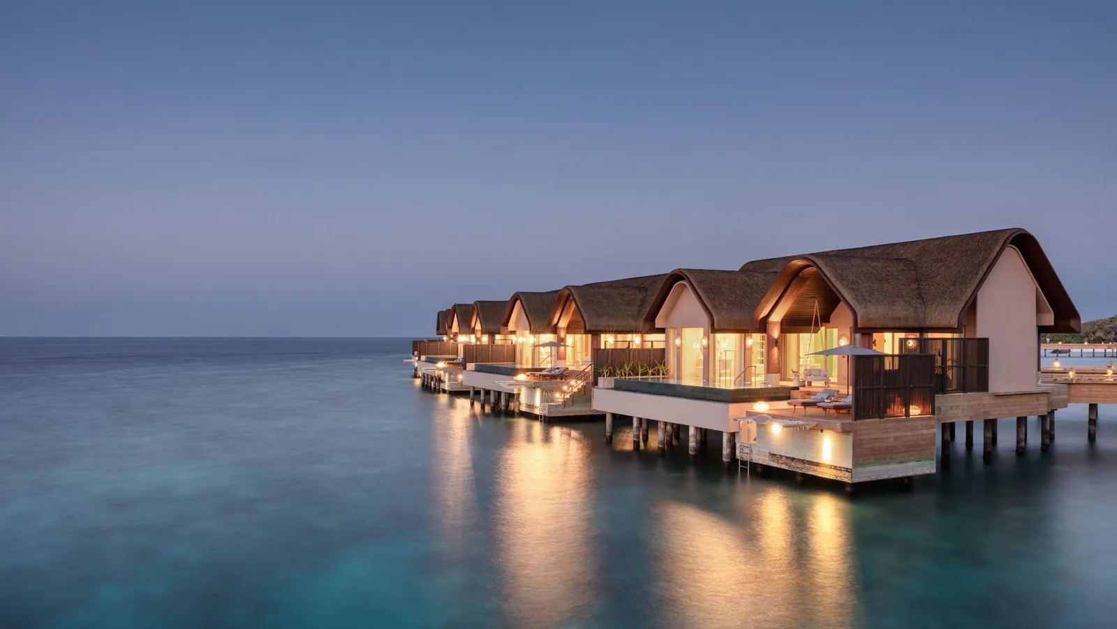 Grand Ocean Pool Villas over the water at dusk, lights on
