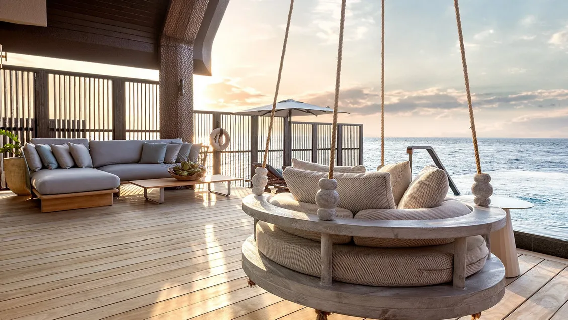 A Sunset Ocean Pool Villa’s deck, its sofa and hanging daybed over the sea
