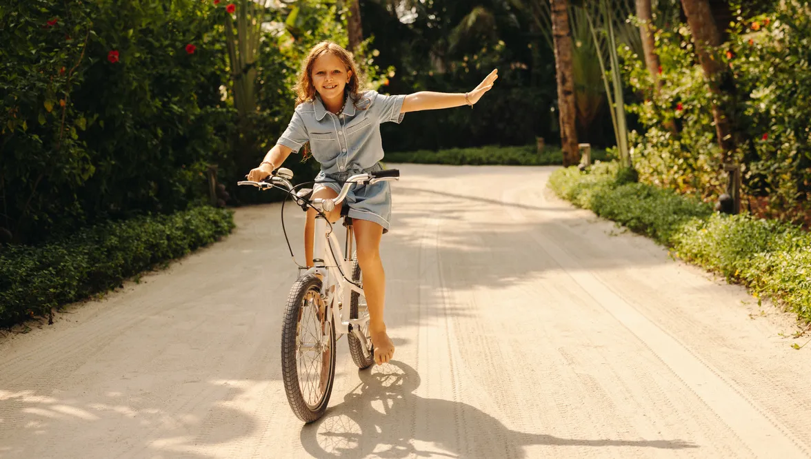 A girl cycling along a sandy path