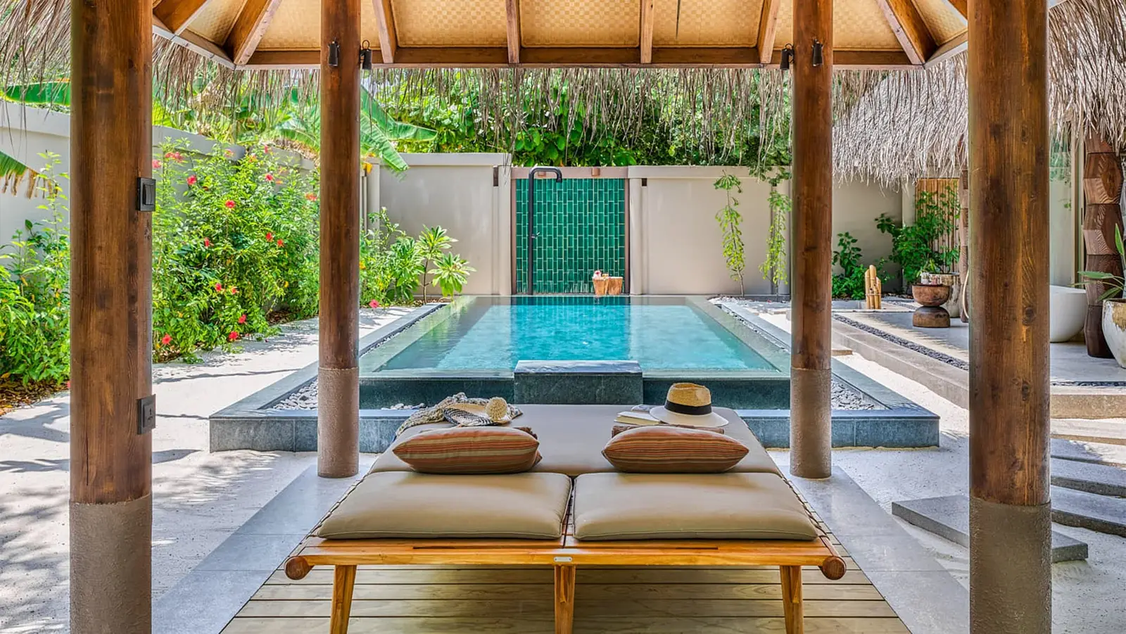 The garden pool of a family villa, under its thatched roof