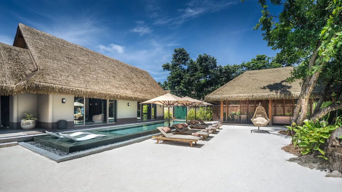 The Three Bedroom Beach Residence from outside, its thatched roof and pool