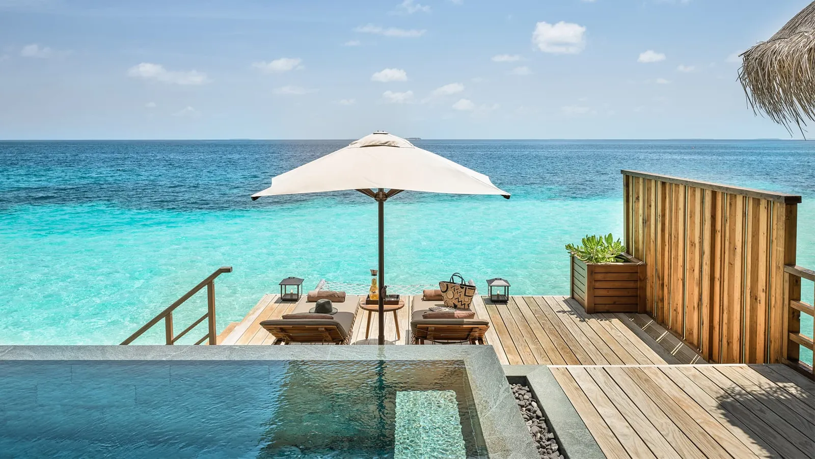 A Water Villa with Pool’s deck, the pool and a parasol over the sea