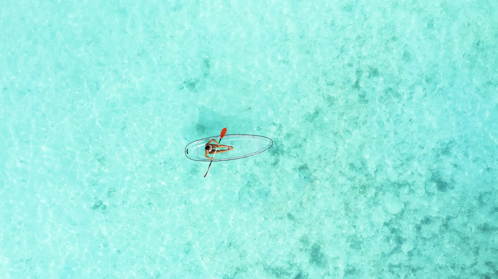 A transparent canoe on the shallow lagoon, seen from above