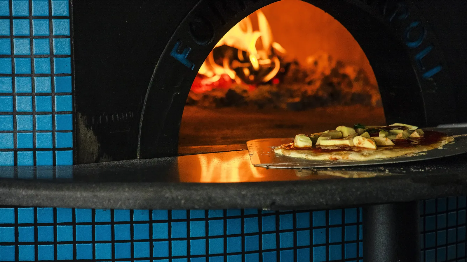 A pizza coming out of Il Basilico’s tiled wood-fired oven