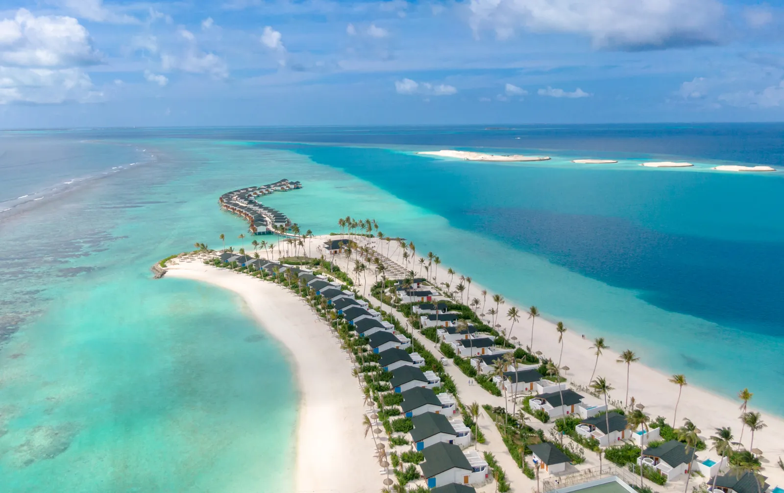 Joy Island’s long white beach, the villas among the palms and the curve of lagoon villas heading out to sea