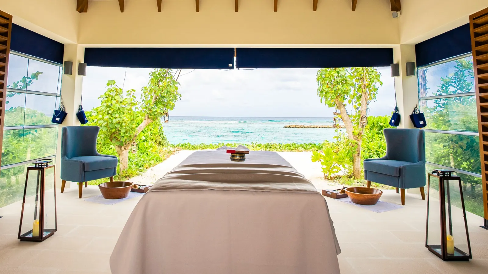 An Oasis Spa treatment bed, 2 blue armchairs and the garden opening onto the sea