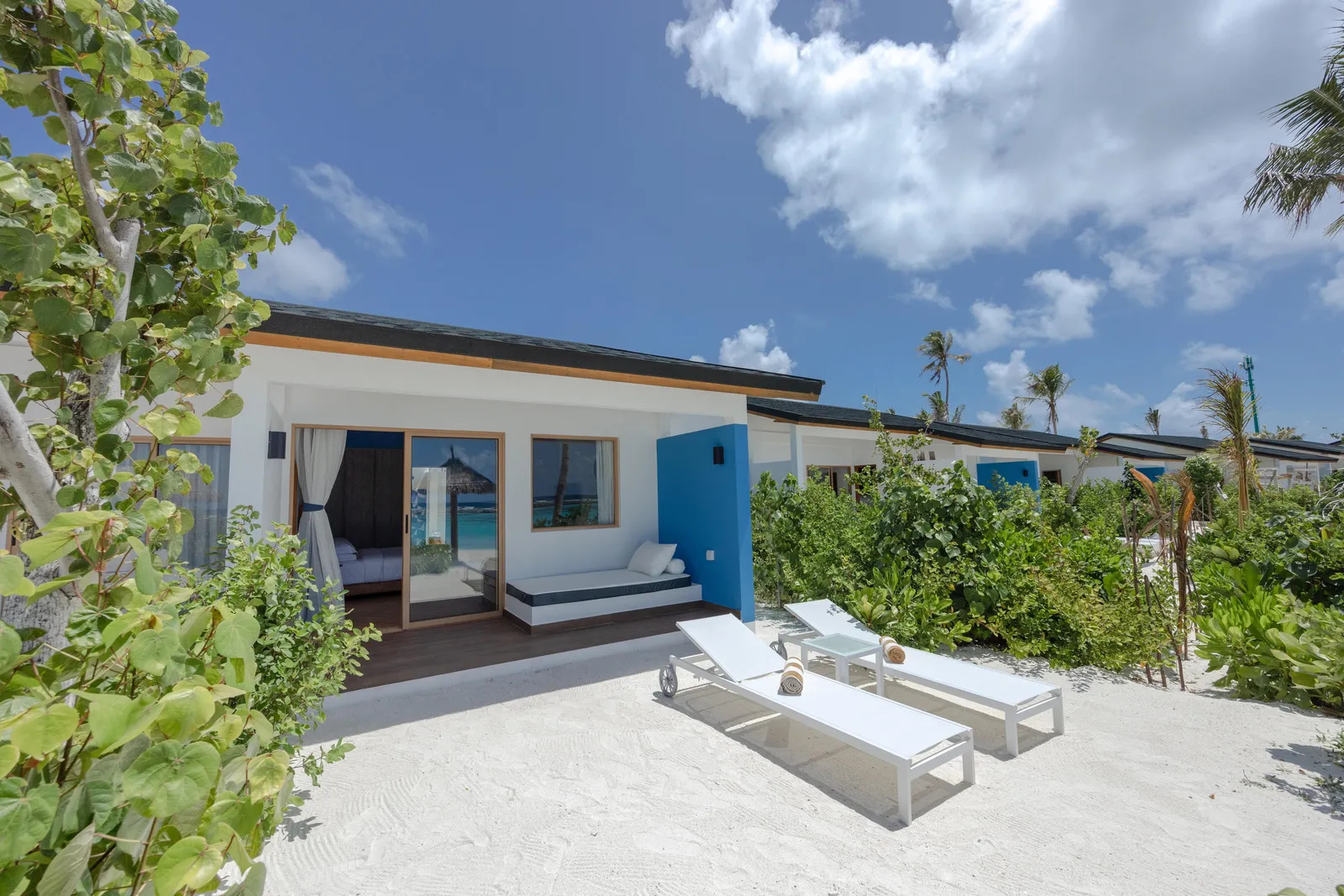 A white Beach Villa with 2 loungers on the sand, among the bushes