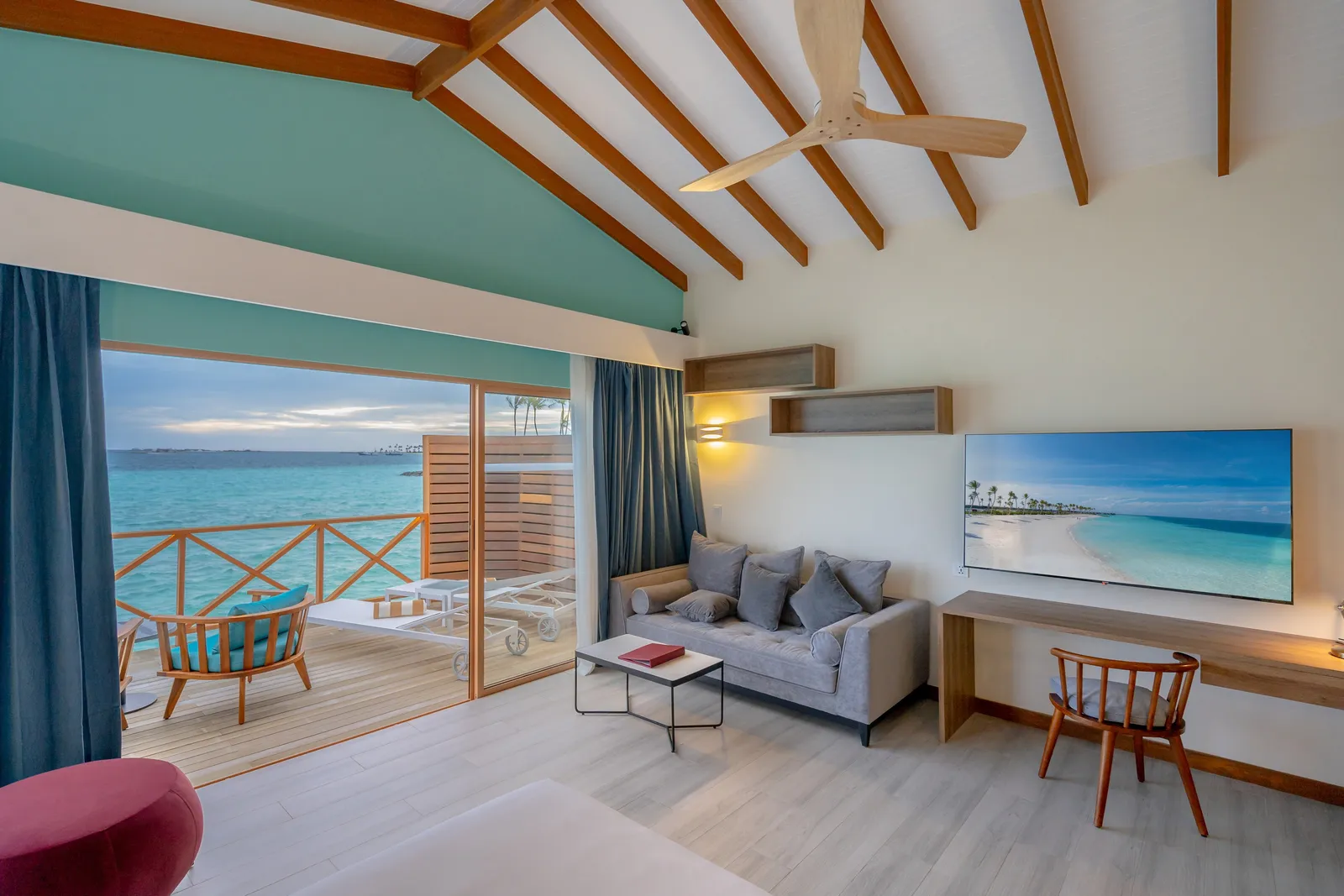 Inside a Lagoon Suite: the bed, the sofa, the desk and the glass doors onto the deck and the sea
