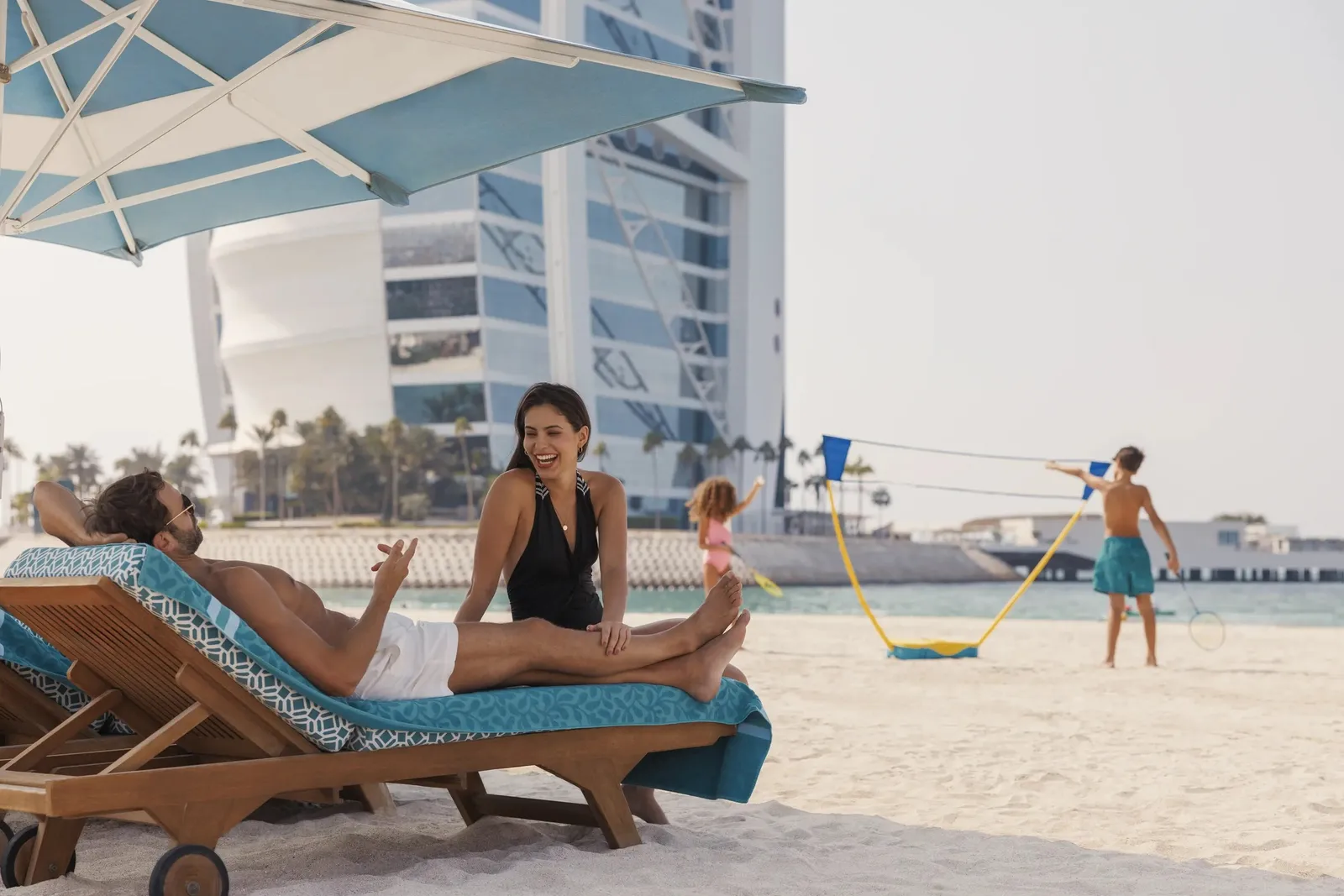 A family on loungers on the beach with the Burj Al Arab behind