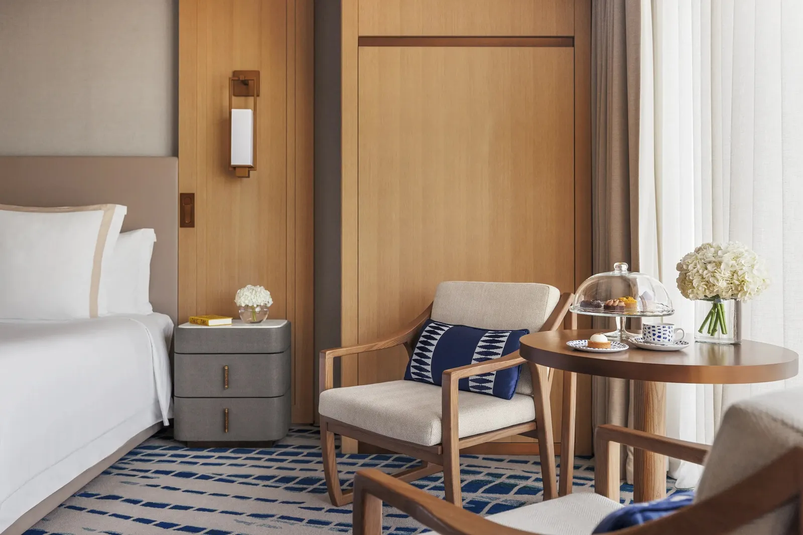 An armchair and a tea table beside the bed in a Club room