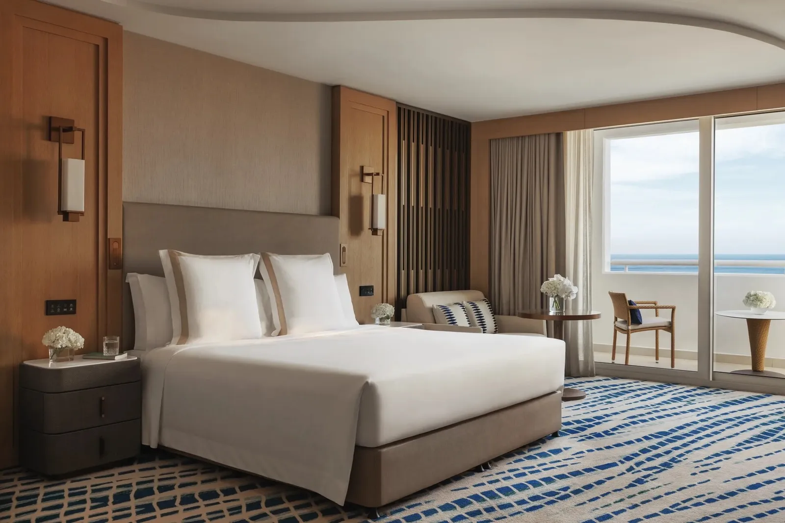 A room with a double bed, an armchair and the door onto the balcony