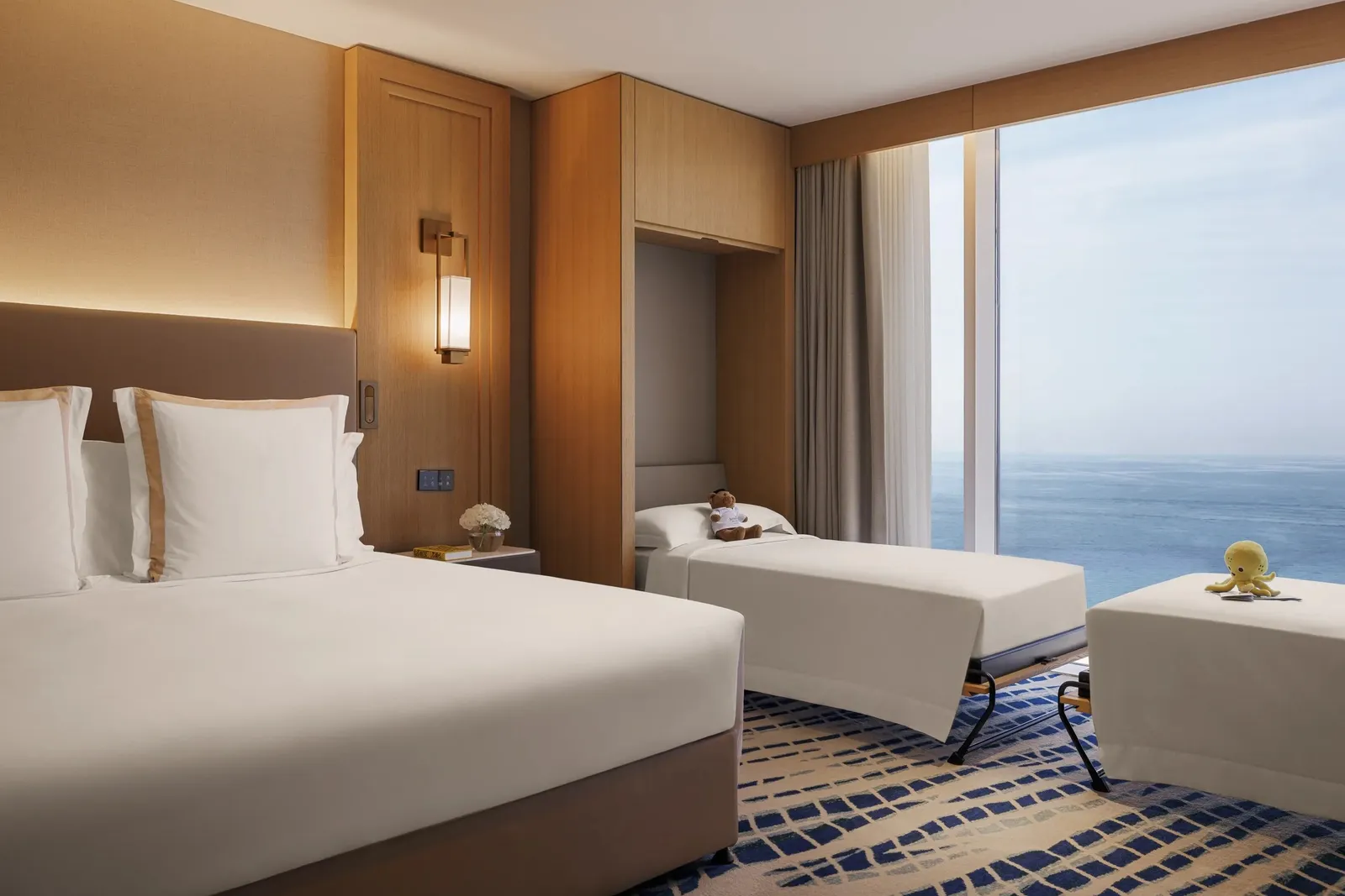 A room with a king bed and a sofa bed under the sea-facing window