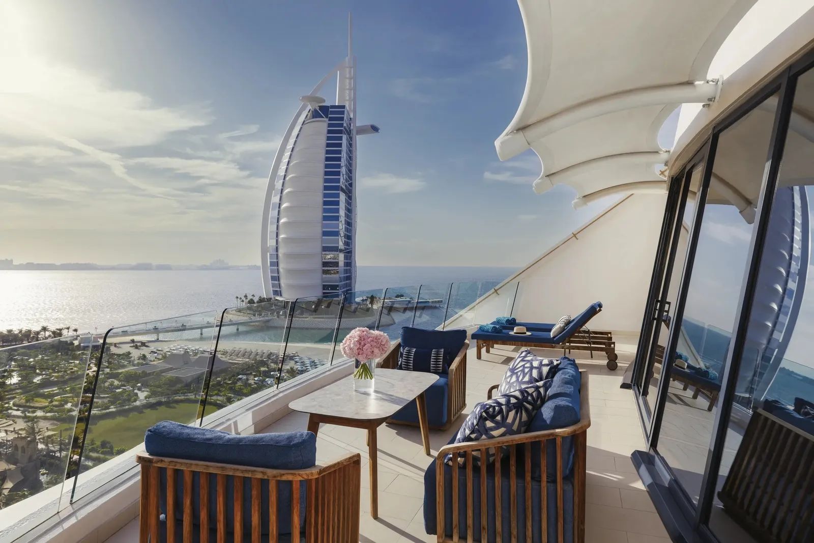 A suite terrace with armchairs and the Burj Al Arab on the sea