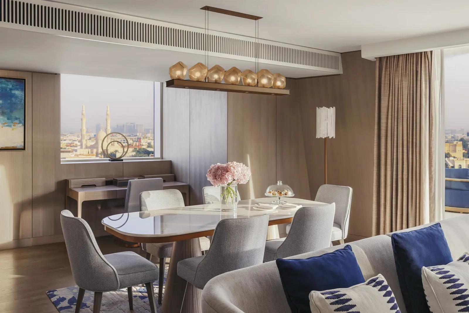 A suite dining room with the table laid and the city through the window