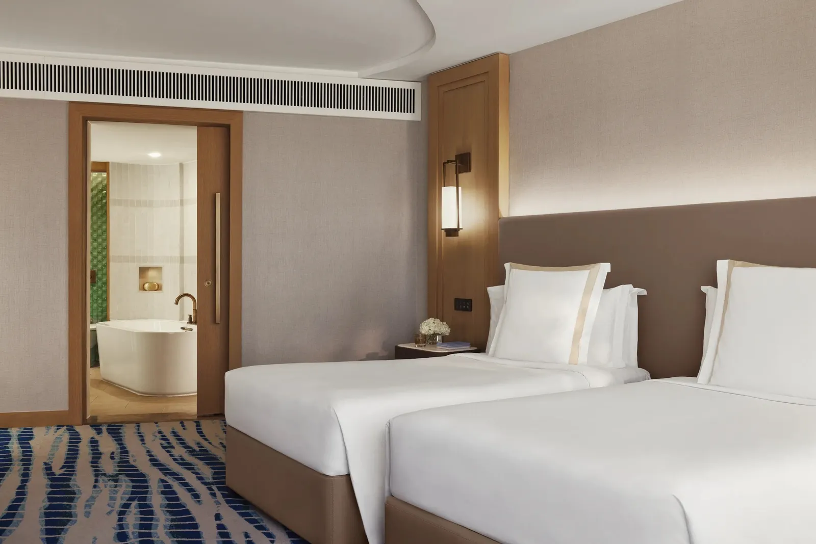 A room with 2 single beds and the door to the second room