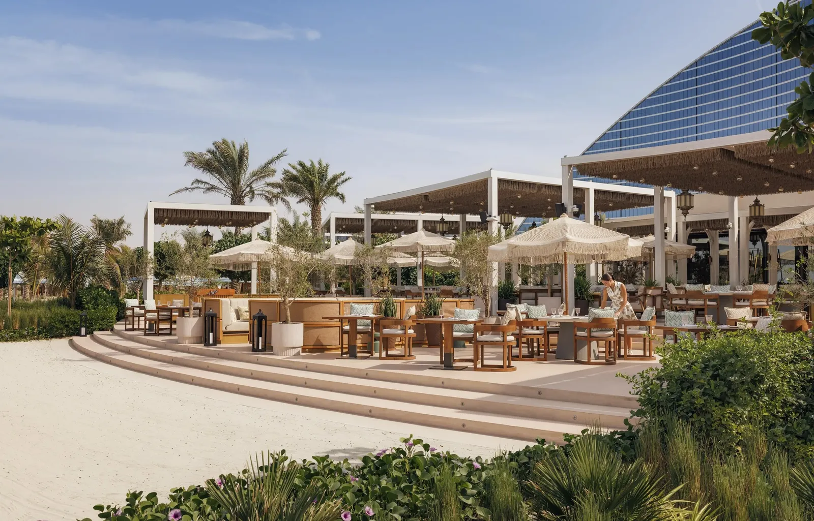 Nuska Beach’s terrace on the sand, with the hotel’s wave behind