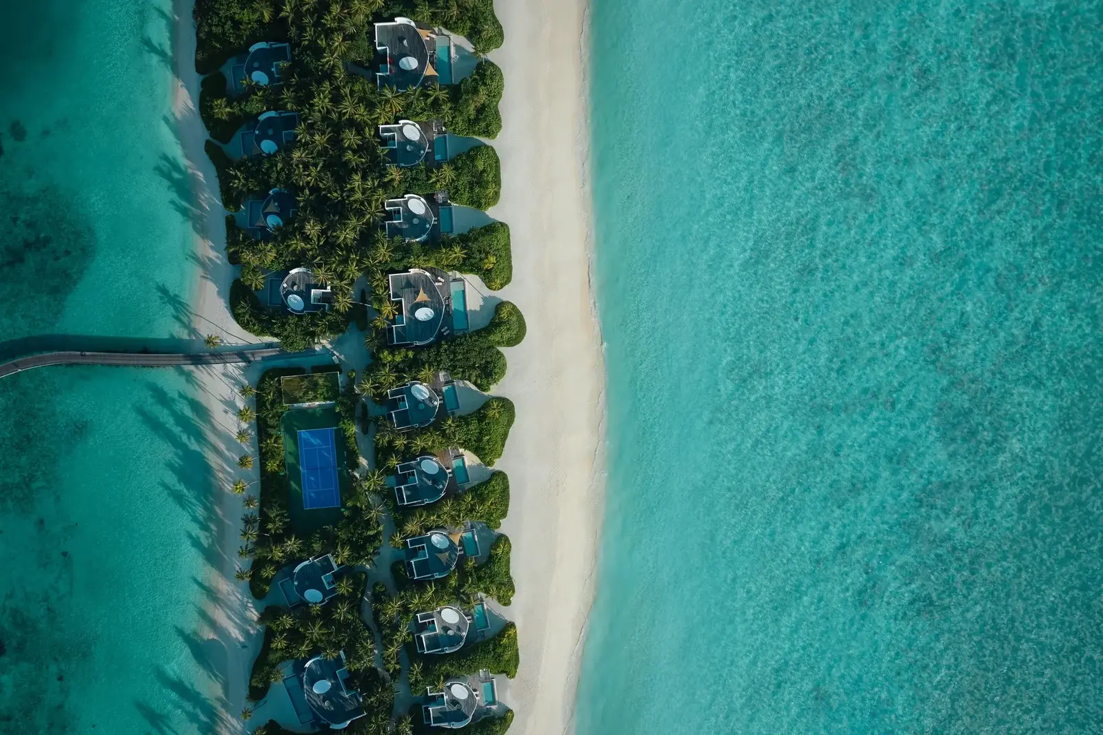 The beach villas from directly above, tucked into greenery between the sand and the lagoon