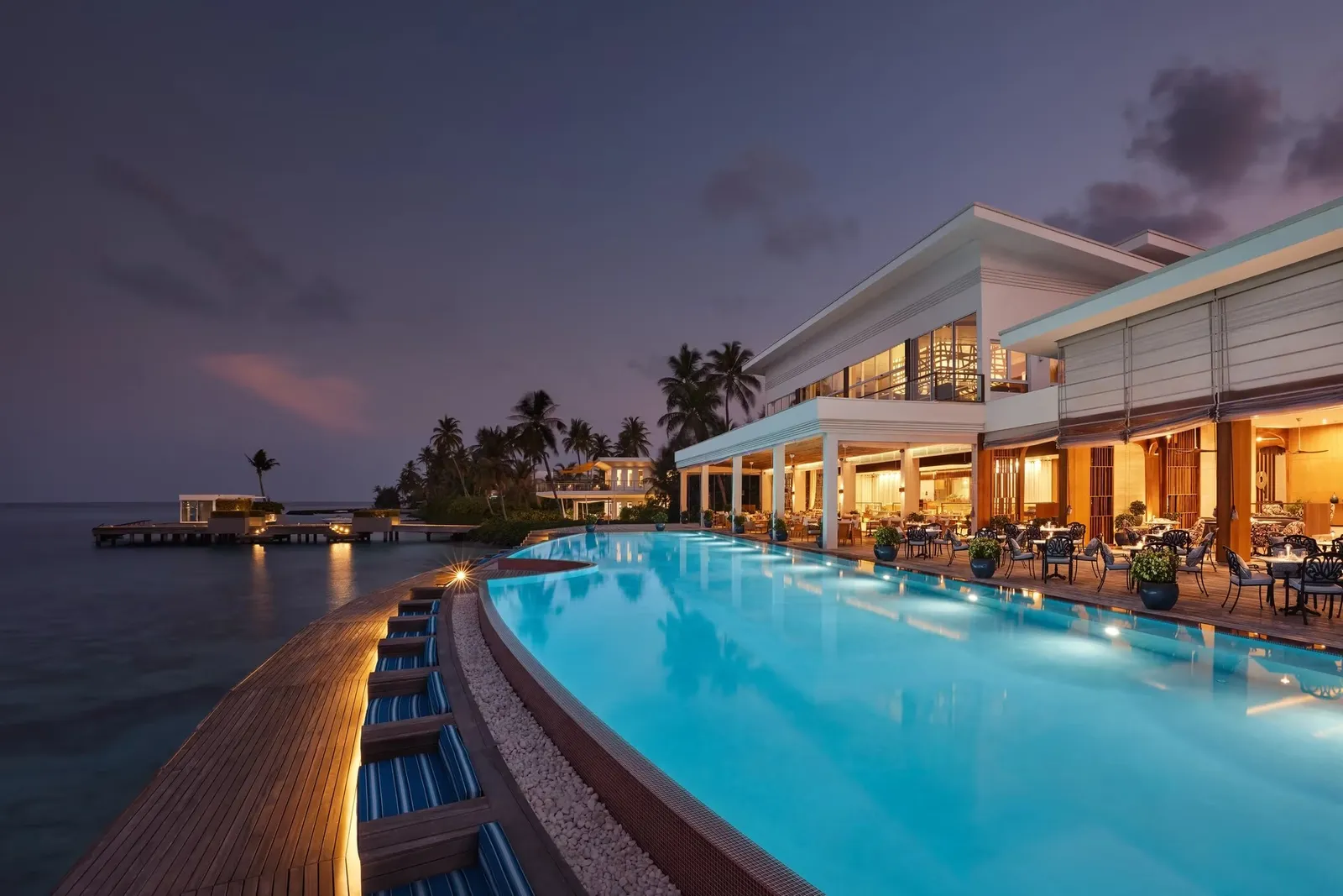 Glow’s infinity pool at dusk, the restaurant lit up beside the sea