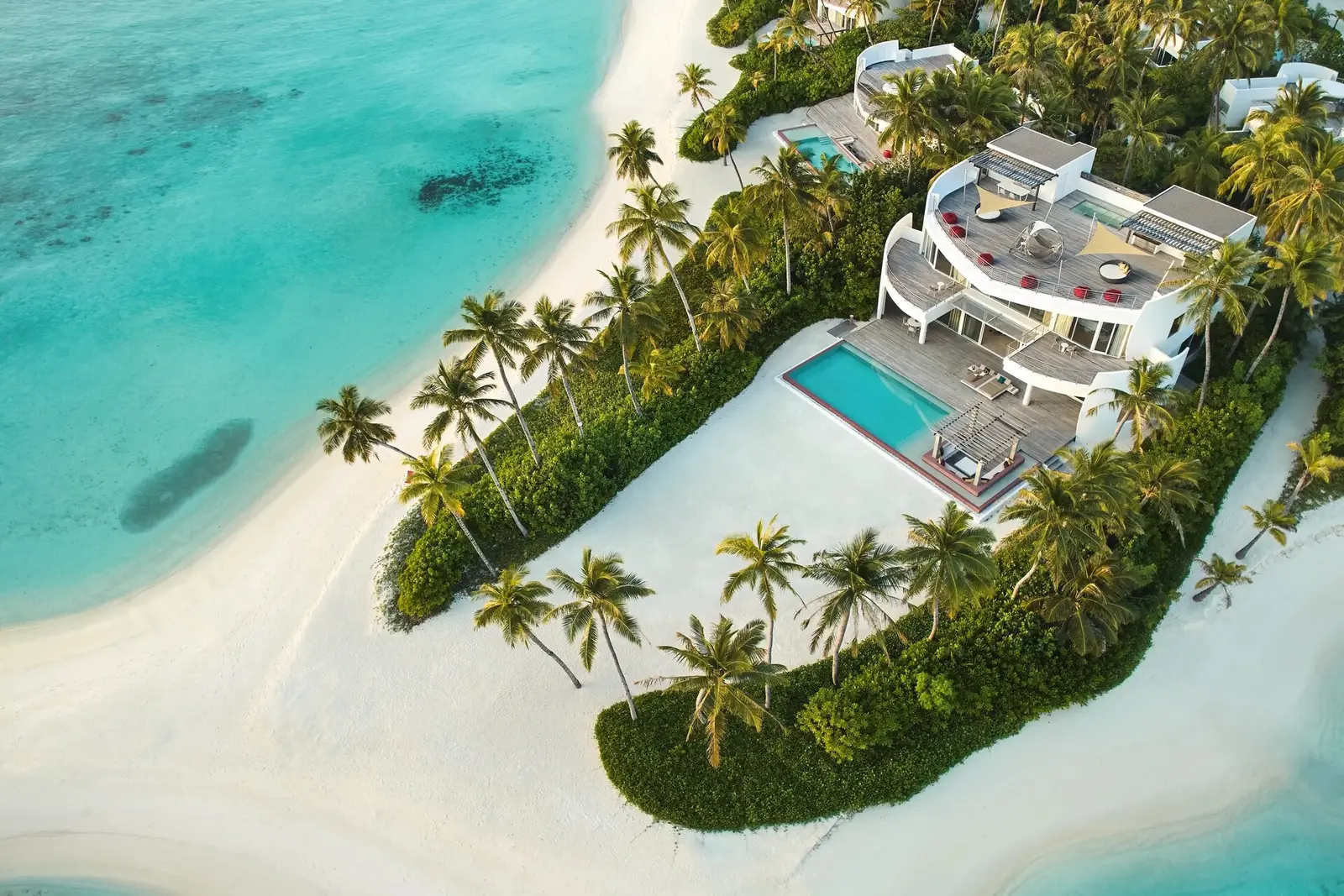 The 3-bedroom beach retreat from above: the tiered white house, the long pool and the sand