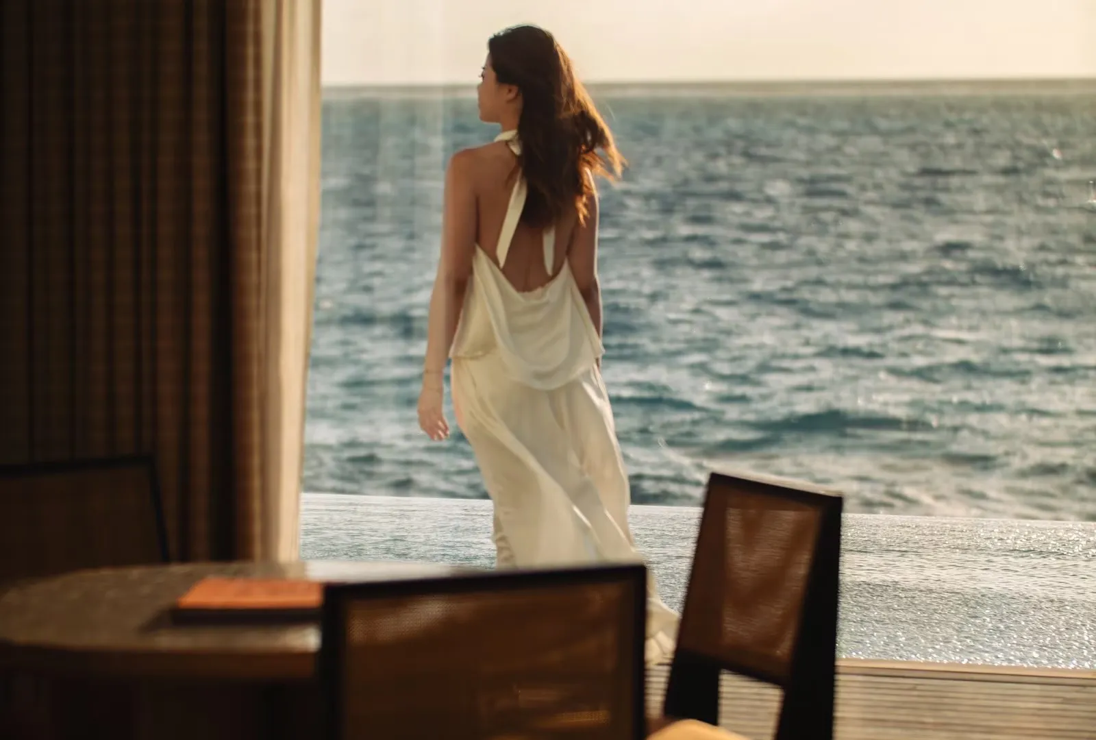 A woman on the timber terrace looking out to sea, beside the villa’s table