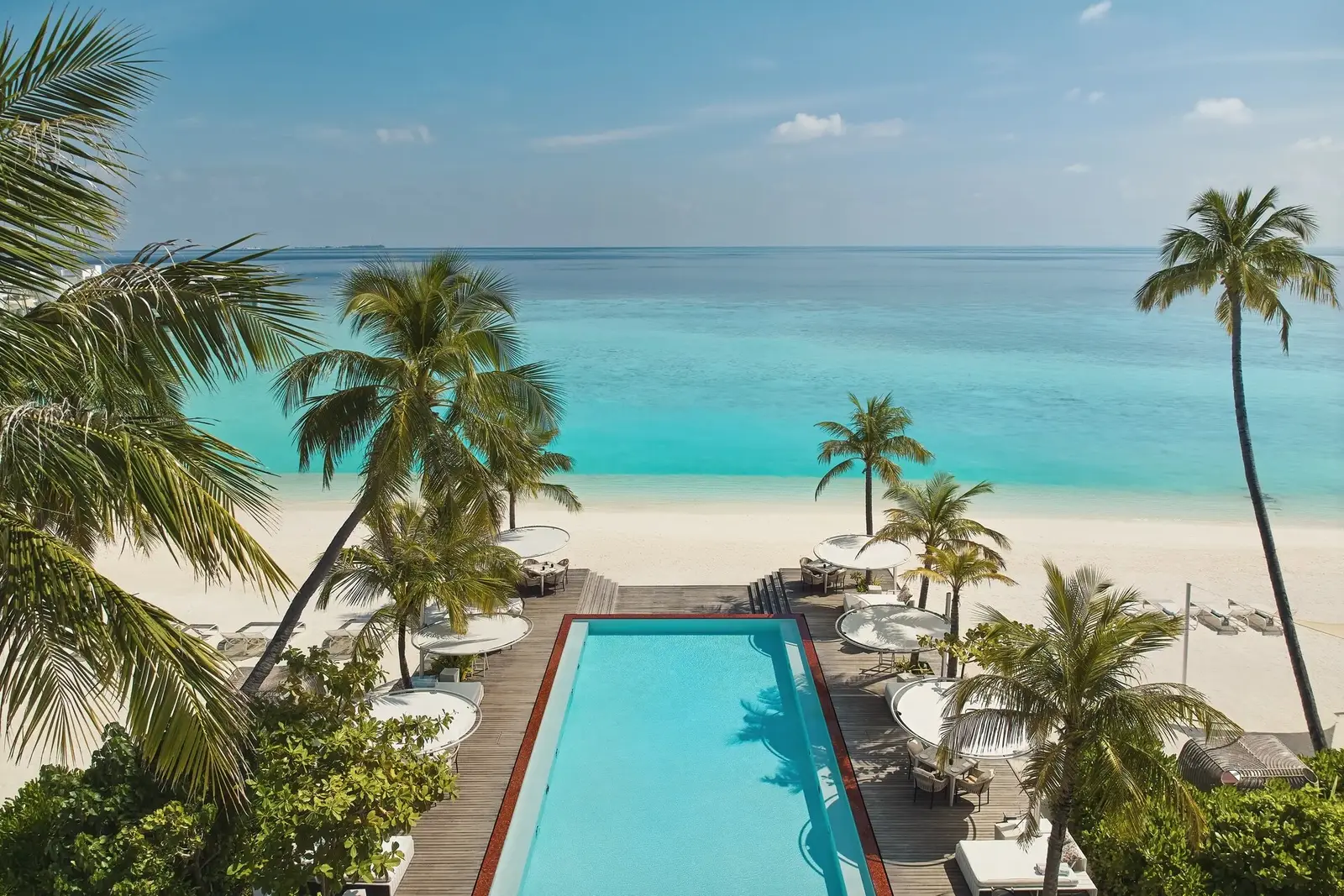 The long pool among the palms, Shimmers’ loungers and the beach on the turquoise sea