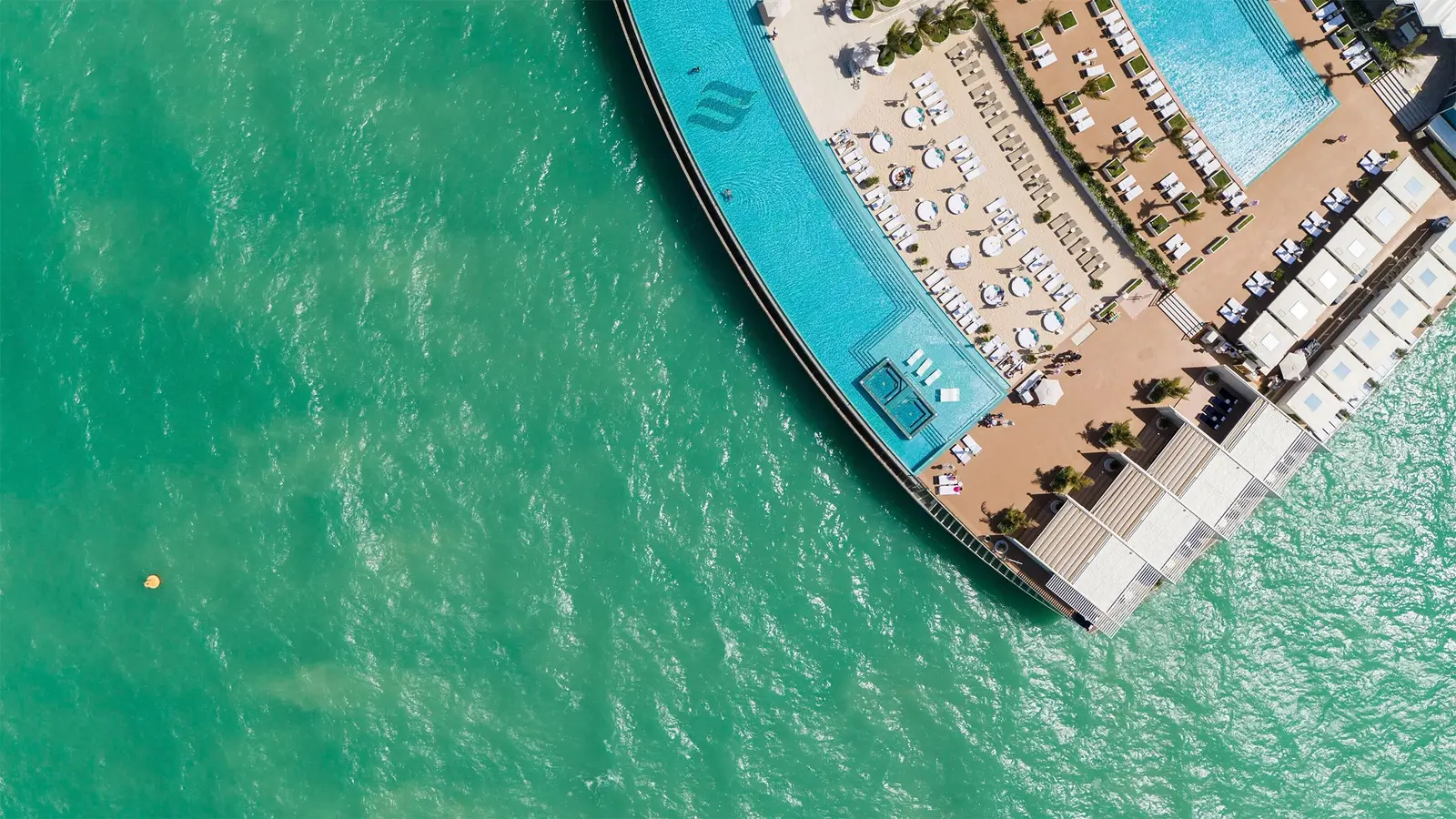 The island from above: the pools, the beach and the marina
