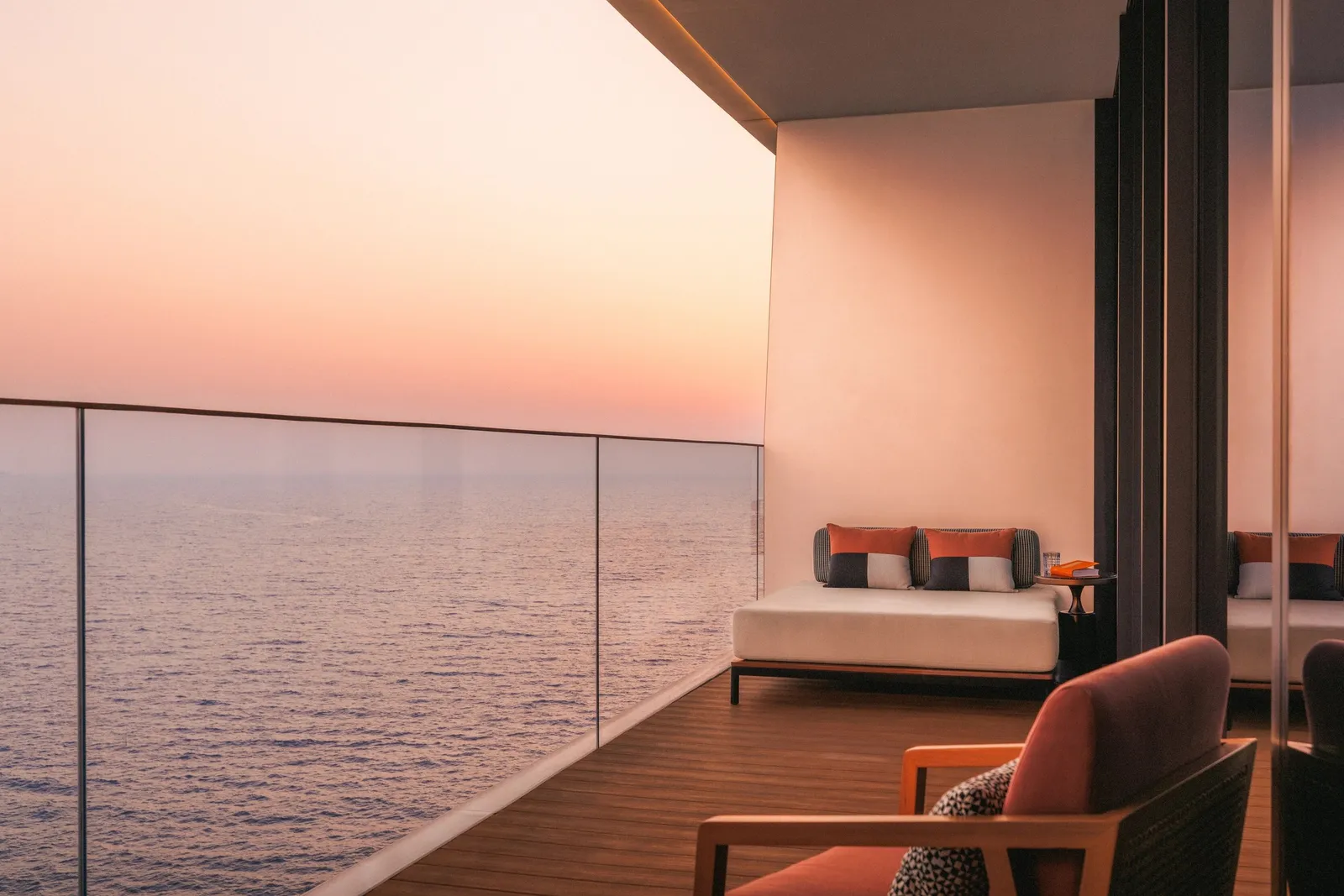 A terrace with a sofa at sunset, the sea pink on the horizon