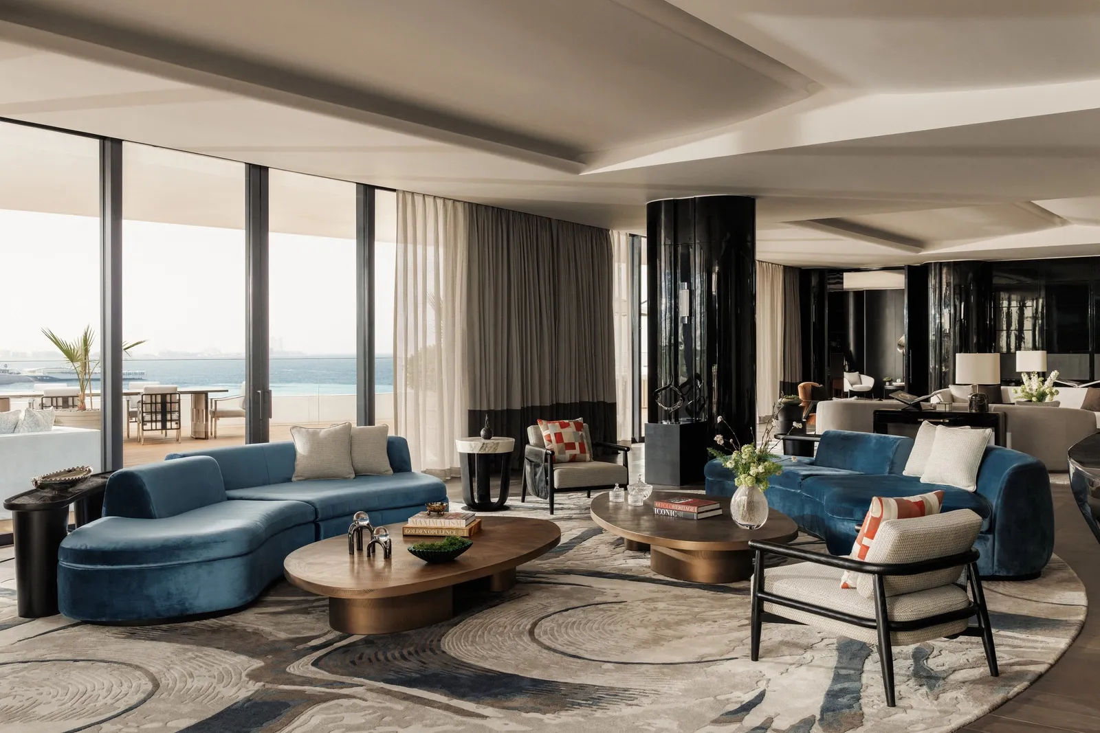 A sitting room with blue sofas and modern chandeliers