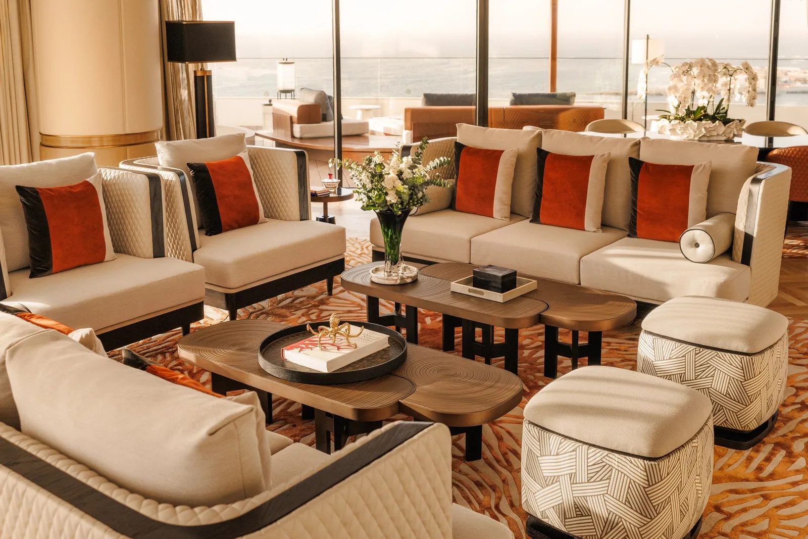 A large sitting room with white sofas and orange cushions