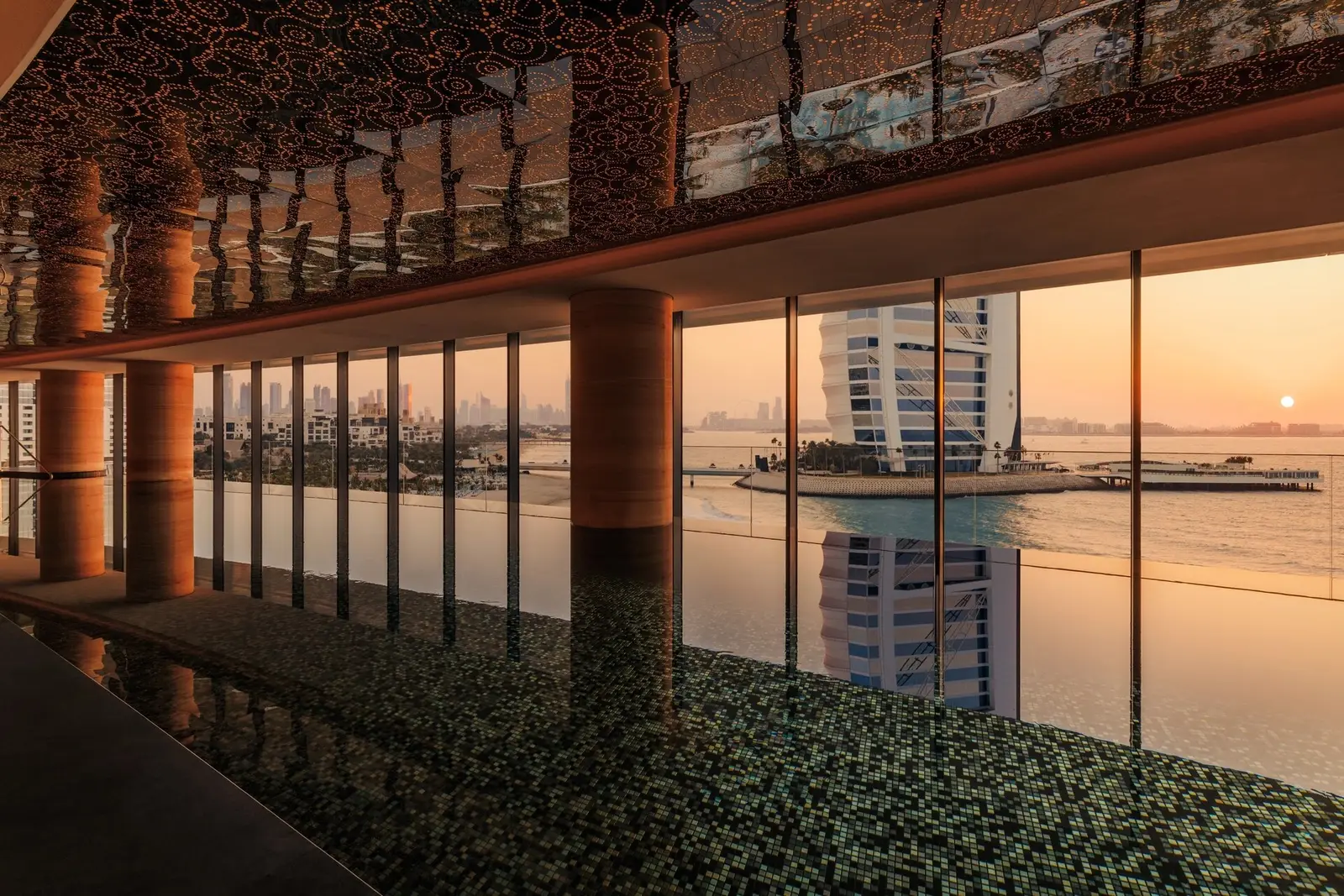 Talise’s 20-metre indoor pool at sunset, the Burj Al Arab through the glass