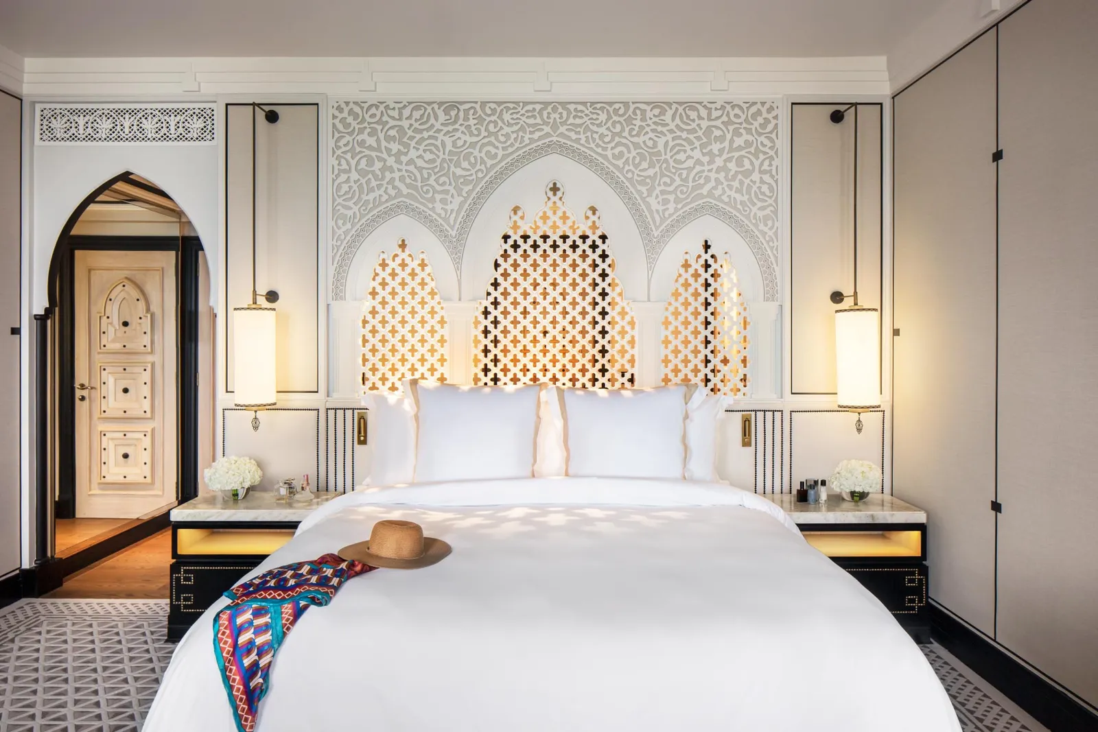 The Deluxe Arabian bed beneath a carved headboard with niches and bedside lamps