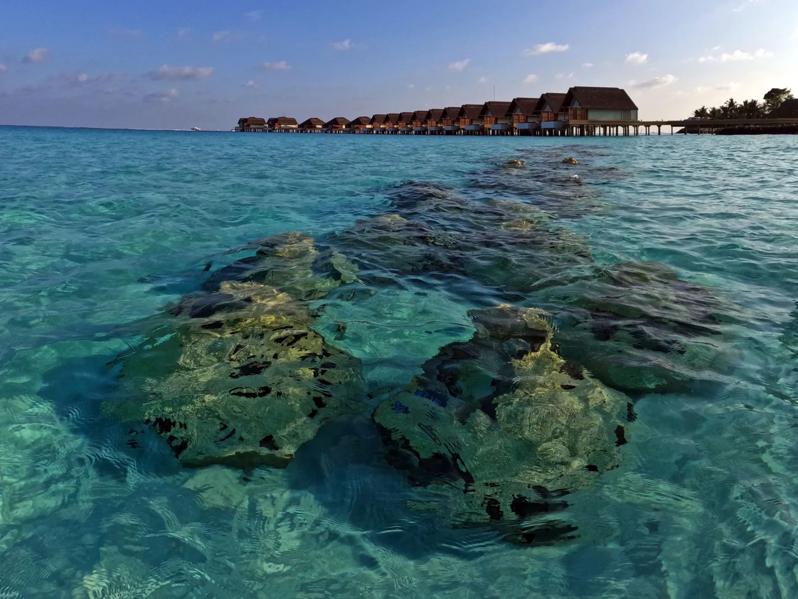 The lagoon with its coral heads from above, the overwater villas on the horizon