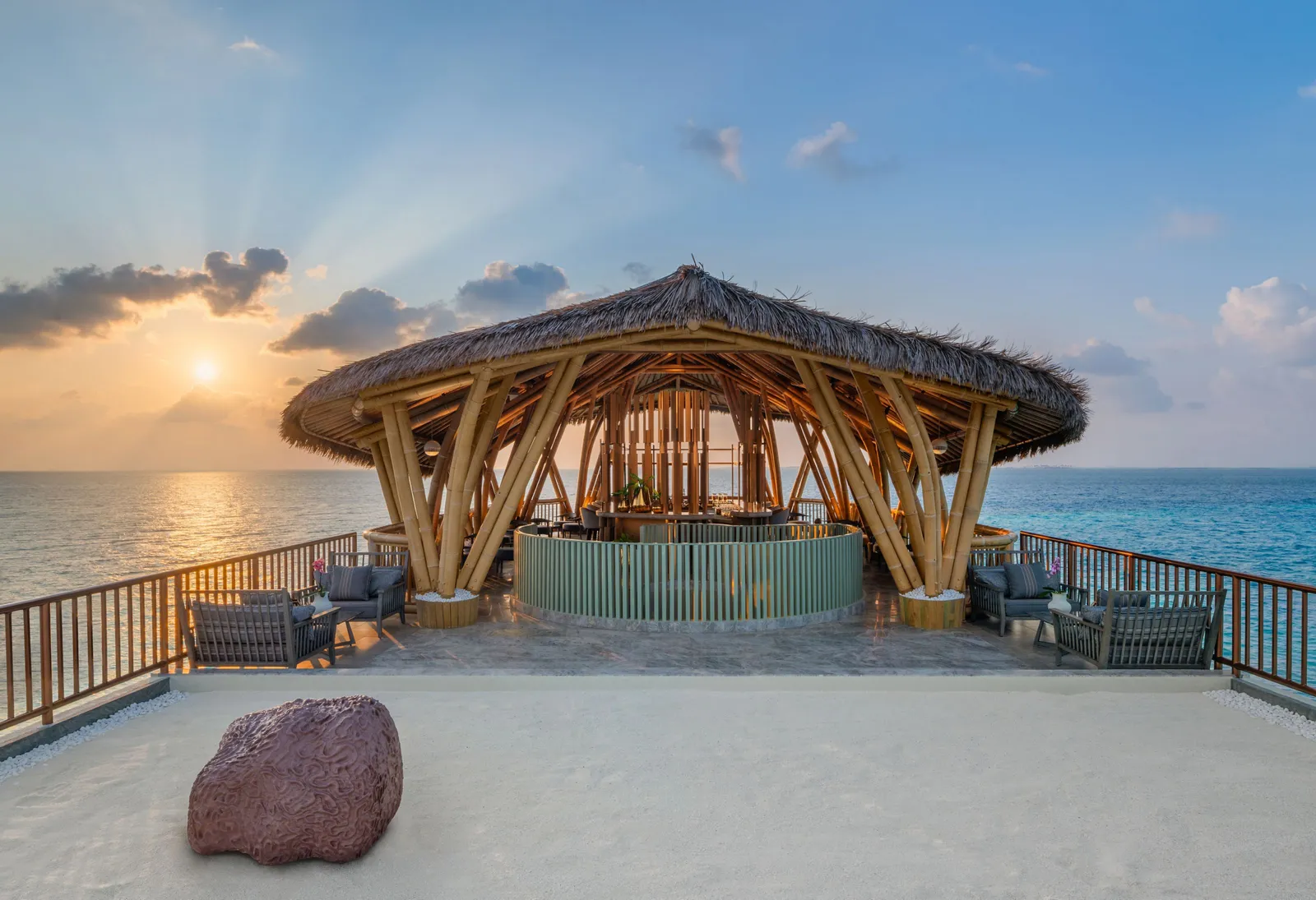 Nikkei’s overwater pavilion at sunset, its woven wooden roof