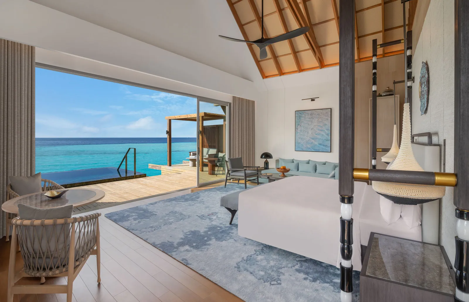 An overwater villa bedroom, the bed and the glass doors open to the deck