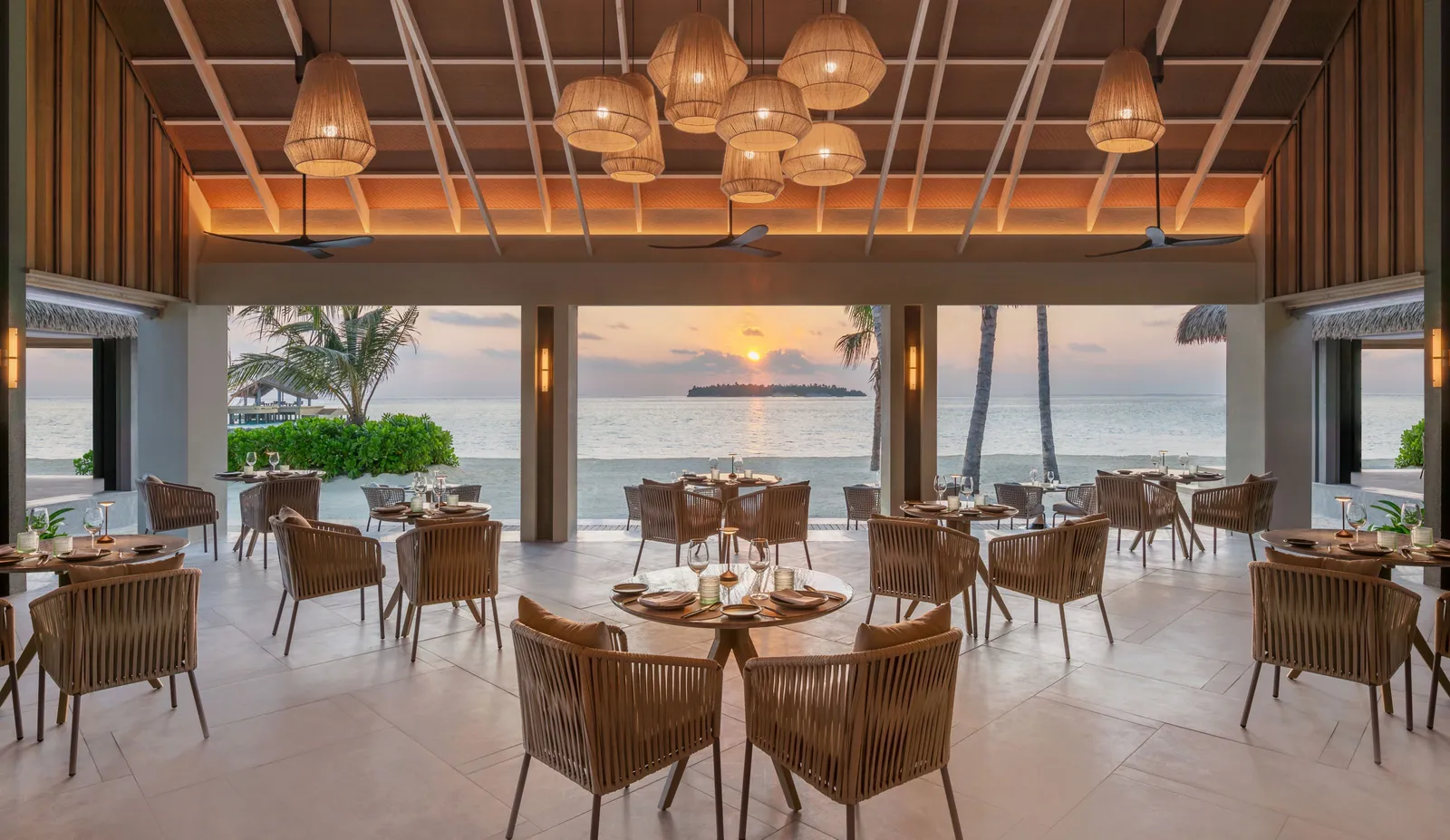 A restaurant hall at sunset, its tables facing the beach