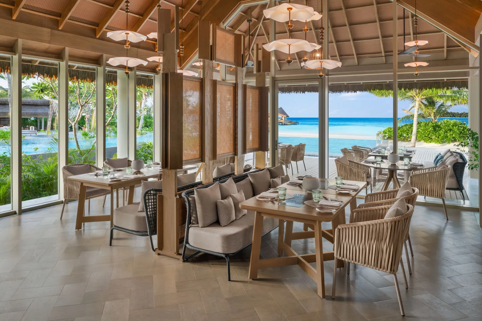 Riva’s dining room, tables laid and windows on the sea