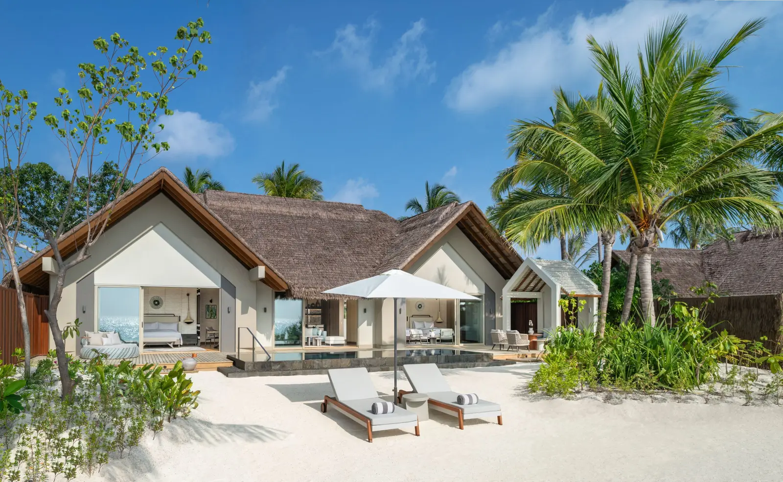 The Two-Bedroom Beach Pool Villa, its thatched roof and loungers on the beach