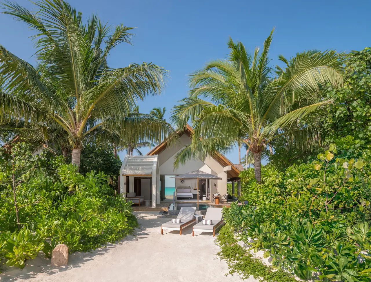 A beach villa seen from the path, among the palms