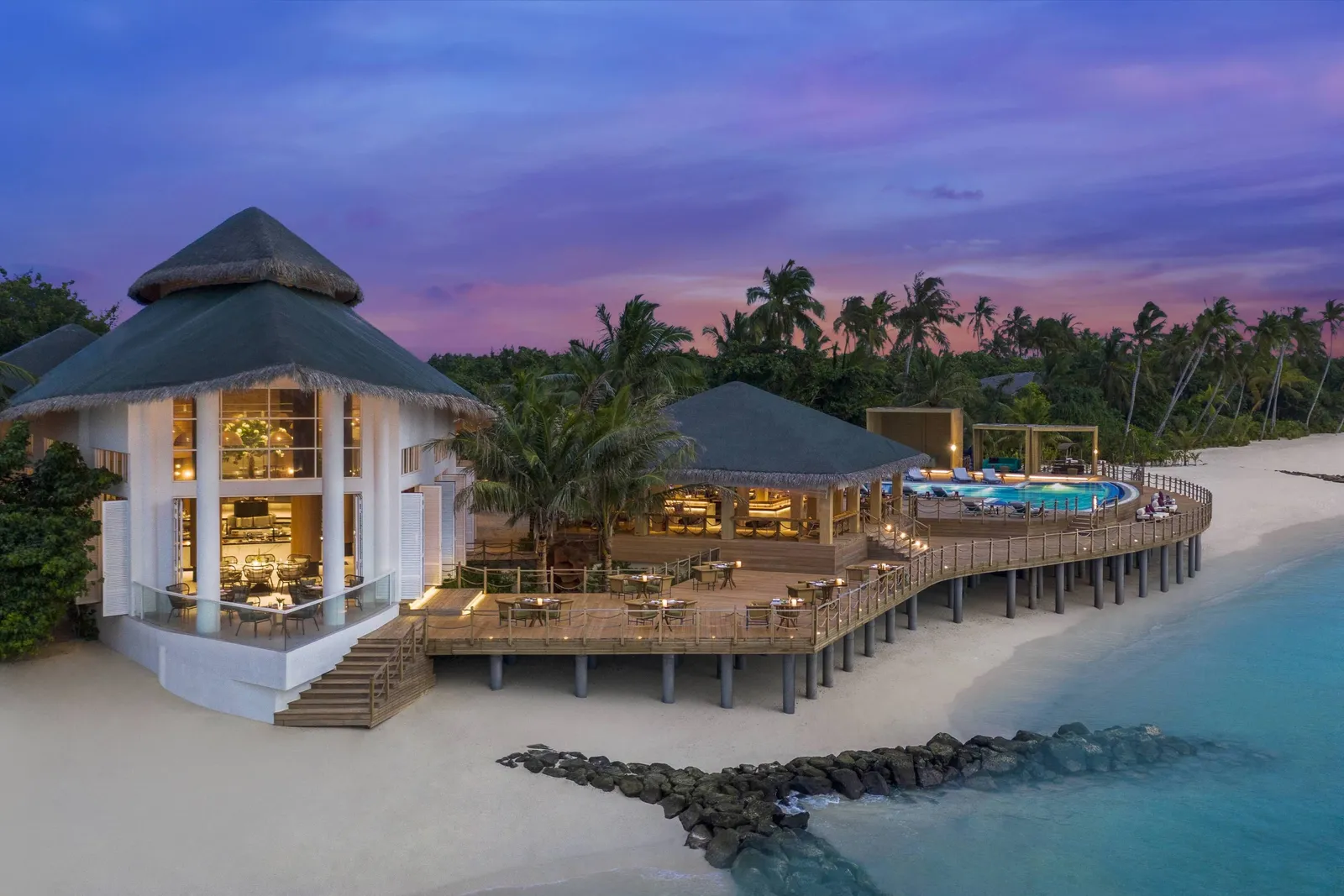 Aailaa at dusk, the pavilion lit up on the beach and the pool beside it