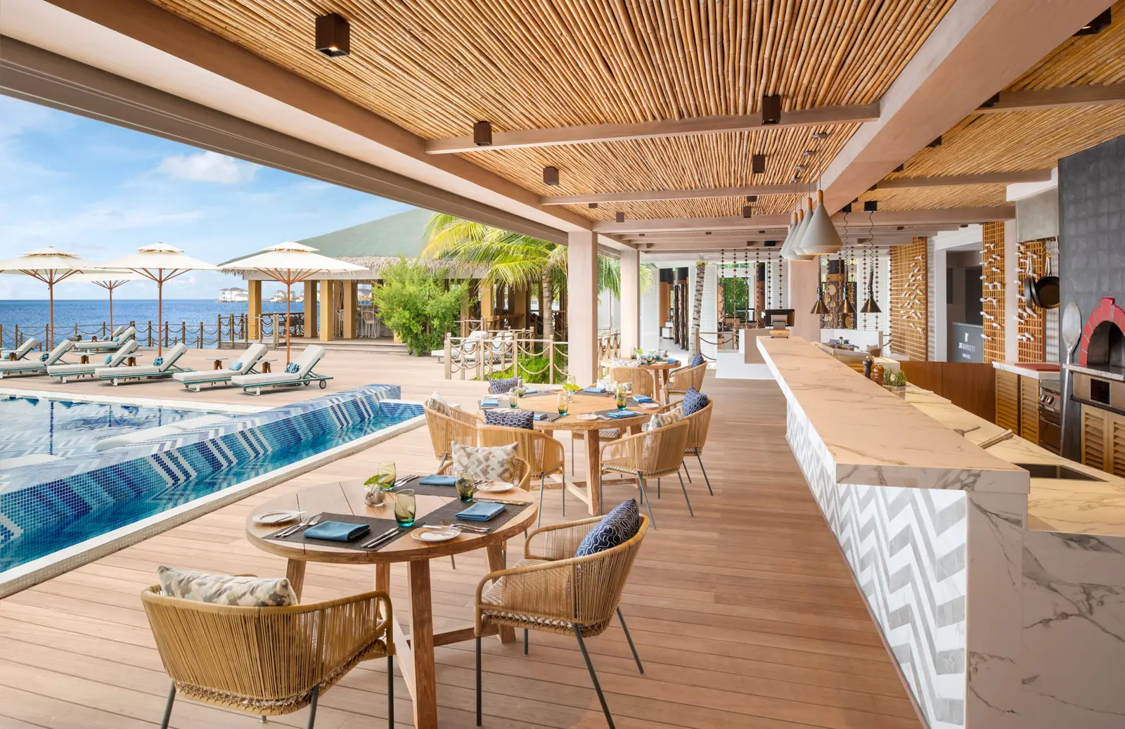 Fiamma’s terrace by the pool, open-air tables under the wooden roof